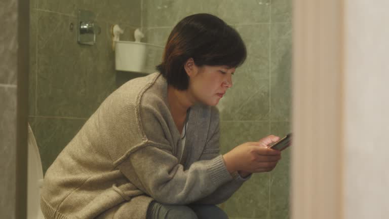 Woman using smart phone in toilet