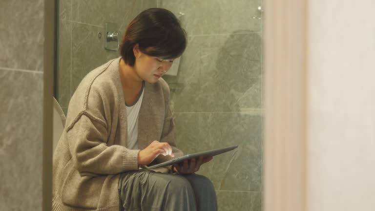 Woman using Digital tablet in toilet