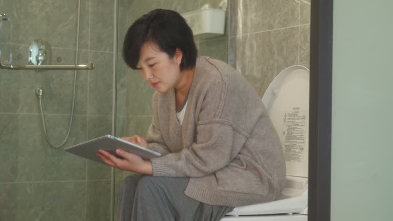 Woman using Digital tablet in toilet