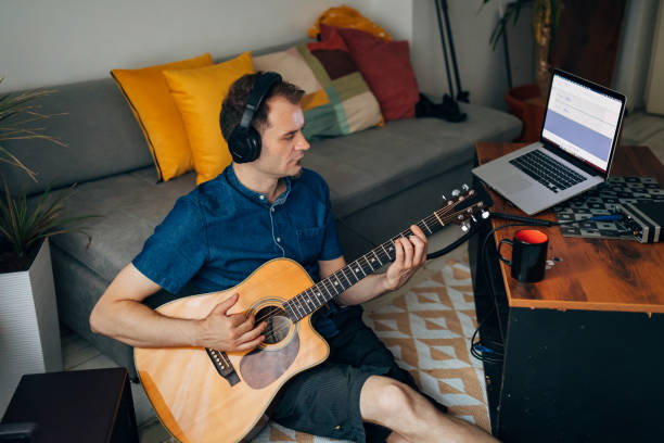 istock Musician using headphones so he can better hear the accords he playing on the guitar 1341844314
