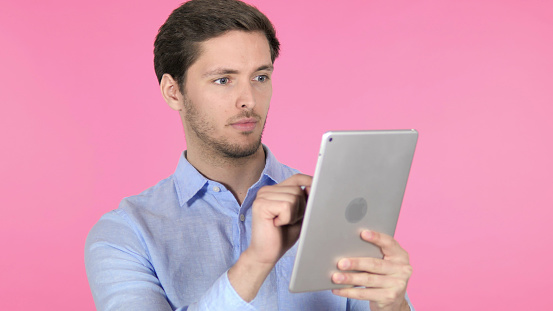 Young Man Using Tablet on Pink Background