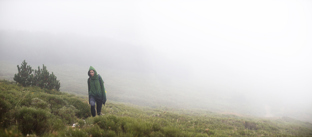 Young woman hiking in the outdoors, through the fog of the Dinaric Alps mountain range in the Autumn.