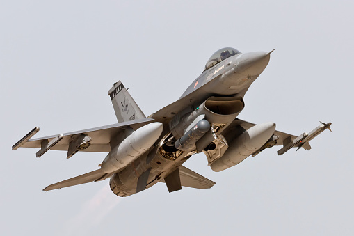 Military figher airplane landing on an airport runway.