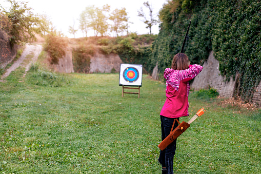 Mature woman shooting bow outdoors on autumn day
