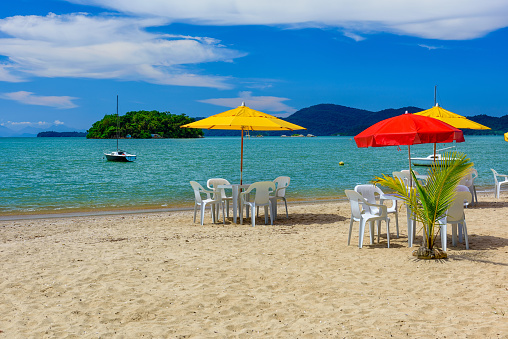 Jabaquara beach with umbrella and chairs in Paraty, Rio de Janeiro, Brazil. Paraty is a preserved Portuguese colonial and Brazilian Imperial municipality