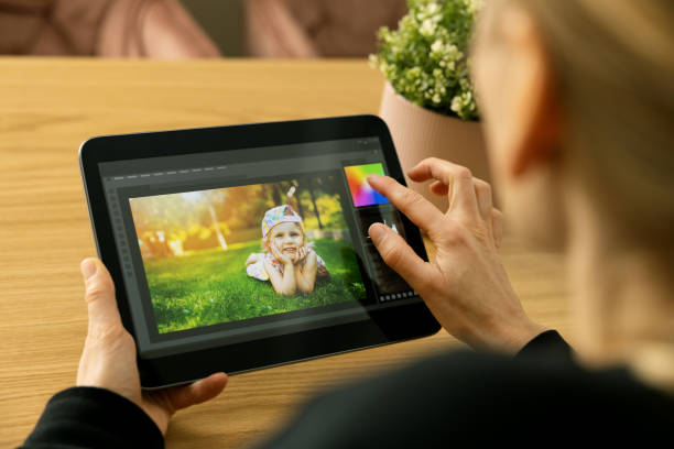 woman photographer using photo editing app on digital tablet stock photo