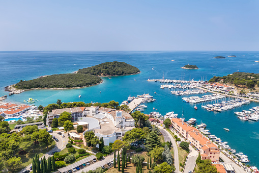 an aerial shot of coastal city Vrsar, boats and yachts in marina, island Sveti Juraj in front side, and several islands on right side, Istria, Croatia