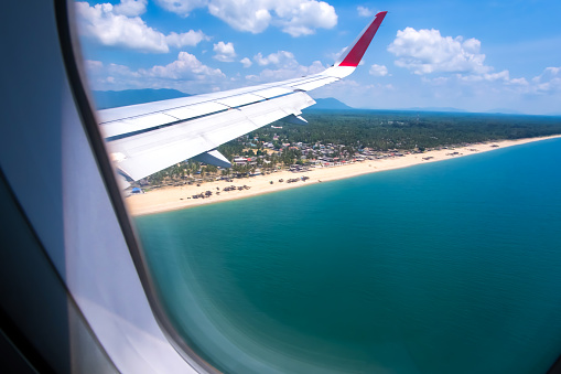 Aerial view of a tropical beach on sunny summer, view from an airplane window.