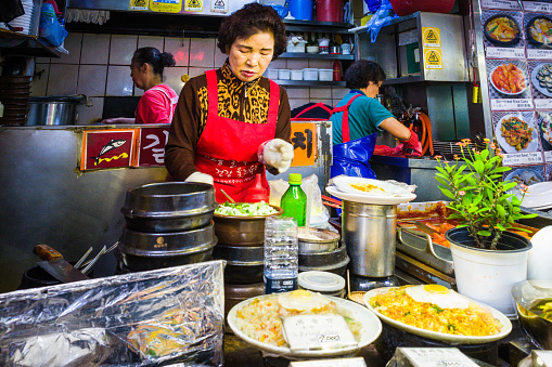 Female cooks preparing food at a busy market stall in downtown Seoul, South Korea.