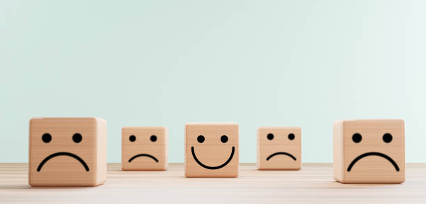 istock Smile face print screen on wooden cube block among sadness face for customer service evaluation and emotion mindset concept by 3d render. 1341855863