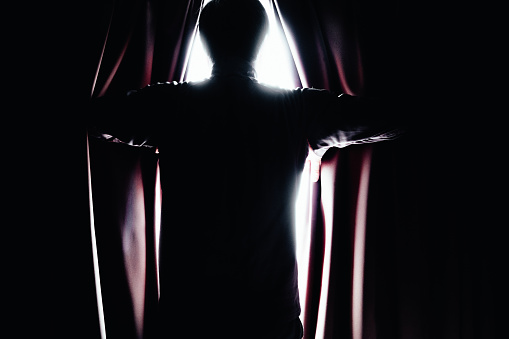 Silhouette of a man opening the curtain