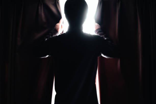 Silhouette of a man opening the curtain