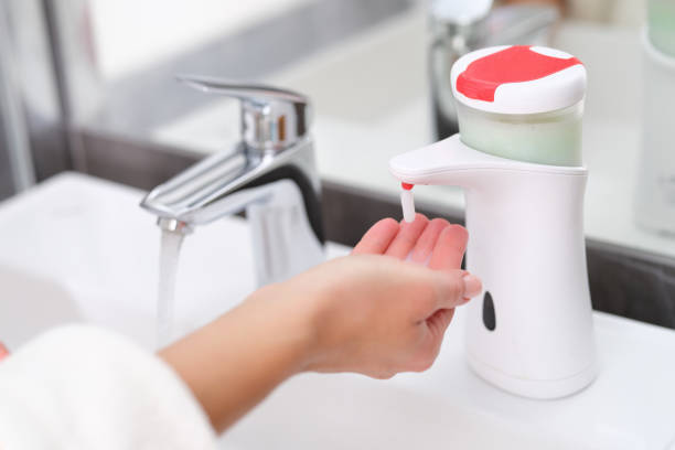 Woman picking up liquid soap from hand dispenser in bathroom closeup Woman picking up liquid soap from hand dispenser in bathroom closeup. Modern hygiene technologies concept soap dispenser stock pictures, royalty-free photos & images