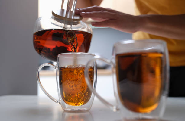 istock Woman pouring black tea from teapot into cup closeup 1341859948