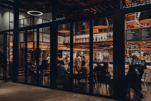 London, UK - September 03, 2021: View from outside of people sitting inside Eataly, a 42,000 square Italian food market in Broadgate that includes restaurants, cookery school and market.