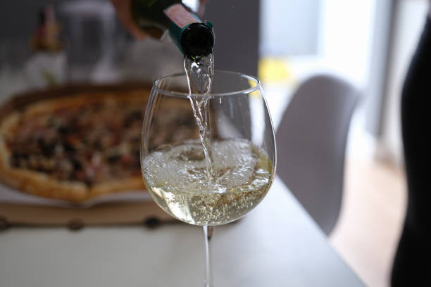 istock White wine pouring from bottle into glass goblet on pizza background closeup 1341860278