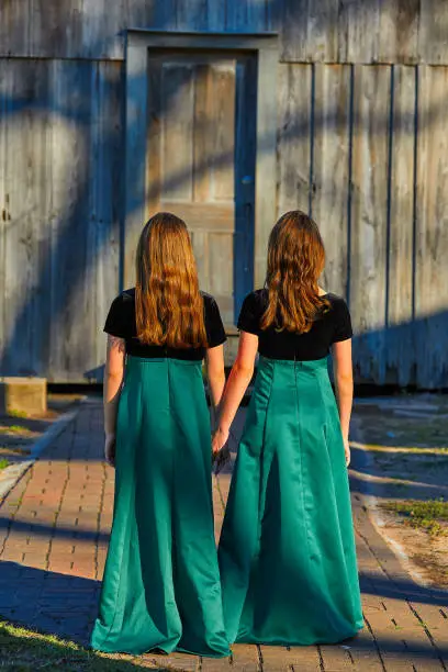Long dress twin teen sisters hand in hand at the park sooden cabin