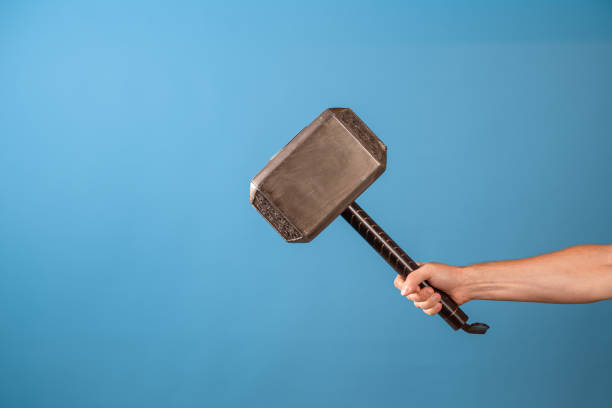 Be a hero, perform a feat. The Scandinavian hammer of Thor, Mjolnir Be a hero, perform a feat. The Scandinavian hammer of Thor, Mjolnir in a man's hand. Photo on a blue background arm hammer stock pictures, royalty-free photos & images