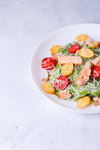 Caesar salad with red fish (salmon, trout), cherry tomatoes, crrumbs, parmesan cheese and romaine salad. Traditional American dish
