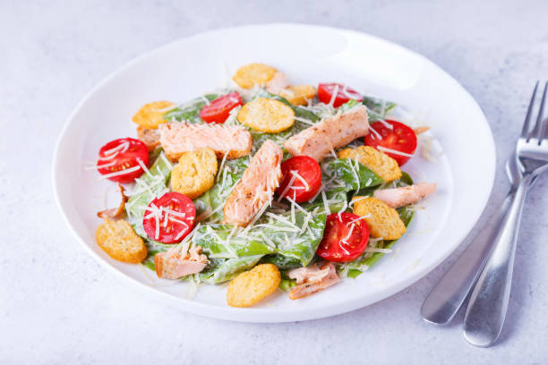 Caesar salad with red fish (salmon, trout), cherry tomatoes, crrumbs, parmesan cheese and romaine salad. Traditional American dish