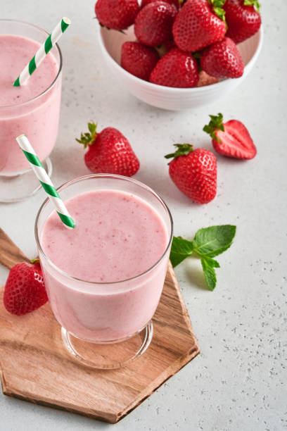 two strawberry smoothie or milkshake with berries and mint in glass on light pink background. summer drink shake, milkshake and refreshment organic concept. healthy dieting, vegetarian food concept. - healthy eating food and drink nutrition label food imagens e fotografias de stock