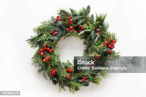 istock Festive Christmas wreath of fresh natural spruce branches with red holly berries. Traditional decoration for Xmas. 1341867273