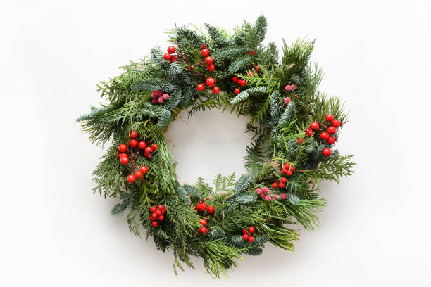 Festive Christmas wreath of fresh natural spruce branches with red holly berries. Traditional decoration for Xmas. Festive Christmas wreath of fresh natural spruce branches with red holly berries isolated on white background. New Year. Top view. Traditional decoration for Xmas holiday. wreathe stock pictures, royalty-free photos & images