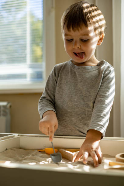 istock Cute toddler playing self development home kinetic sandbox use Maria Montessori method 1341867317
