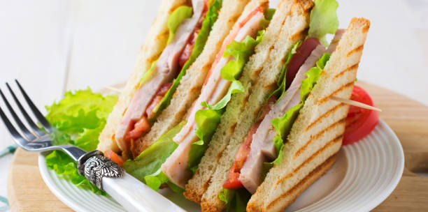 istock Sandwich for breakfast with stuffed tomatoes with ham and lettuce on a light wooden background. Selective focus. 1341867392