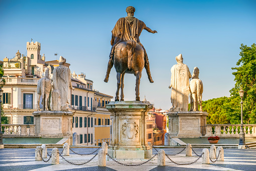 A view of the majestic equestrian statue of Emperor Marcus Aurelius, located in the center of Piazza del Campidoglio (the Roman Capitol Square) on the Capitoline Hill, designed by Michelangelo in 1534 in the heart of ancient Rome. The original statue of Marcus Aurelius is kept inside the Capitoline Museums, a few meters away. On the sides, placed at the top of the steps of the Capitoline Hill, the Roman monumental statues of Castor and Pollux, coming from the Circus Flaminio. In 1980 the historic center of Rome was declared a World Heritage Site by Unesco. Image in high definition format.