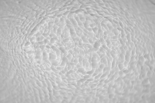 Water tranquil ripple background. Water texture, circles and bubbles on a liquid white surface. Cosmetic products and flat design concept. High quality photo