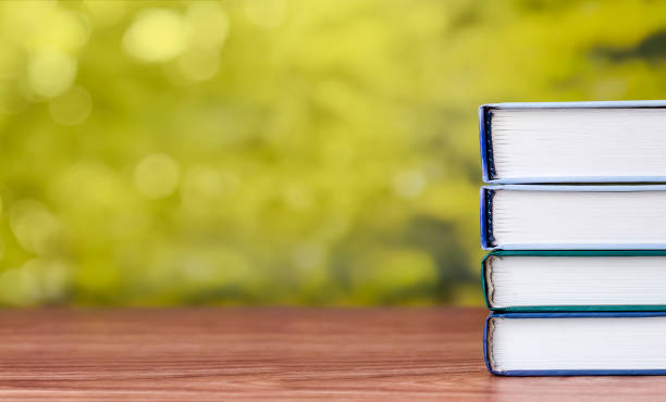 A stack of books on a wooden table with place for text.