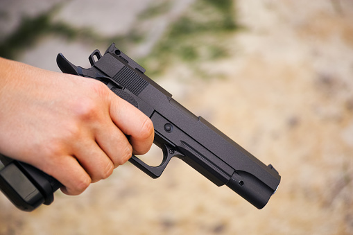 Realistic black airsoft gun in person hand. Close-up