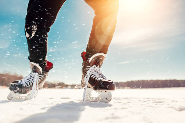 Close-up skates at speed in a bend with flying snow Outdoor ice hockey of a frozen lake on a sunny day - close-up skates at speed in a bend with flying snow skater feet stock pictures, royalty-free photos & images