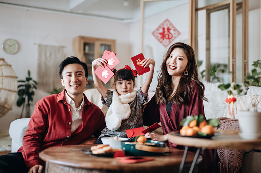 Joyful Asian family holding red envelops (lai see) and celebrating Chinese New Year together