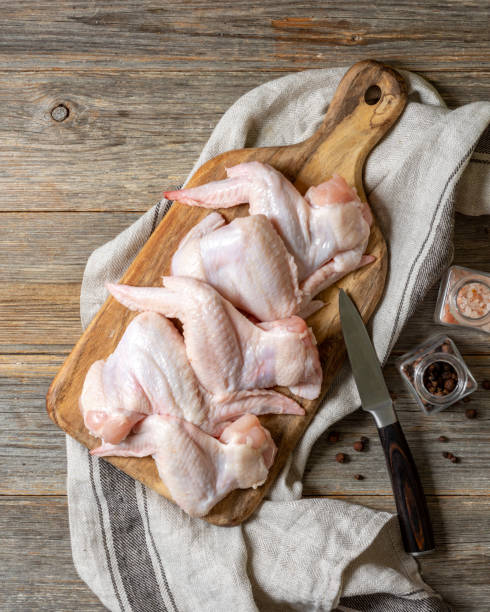istock Raw chicken wings on a wooden board on a light gray culinary background close-up. The process of cooking poultry 1341878850
