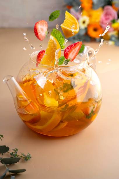 Fruit tea in glass teapot with floating fruti slices and tea splashes. Levitation.