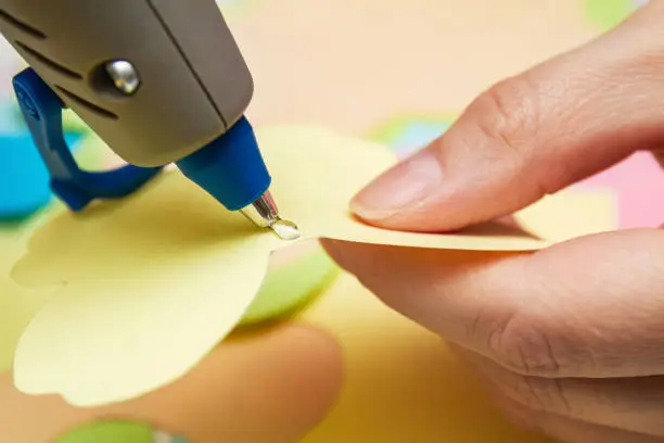 Photo of Woman uses hot melt glue gun in handmade applications. Closeup, selective focus