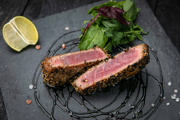 istock Tuna with lemon and salad on a dark table 1341880333