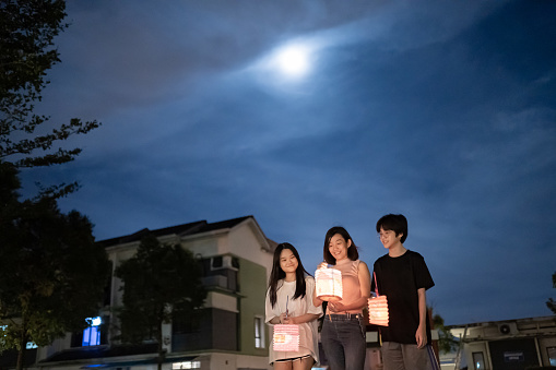 Asian Chinese mother with children holding paper lantern, celebration mid autumn festival.