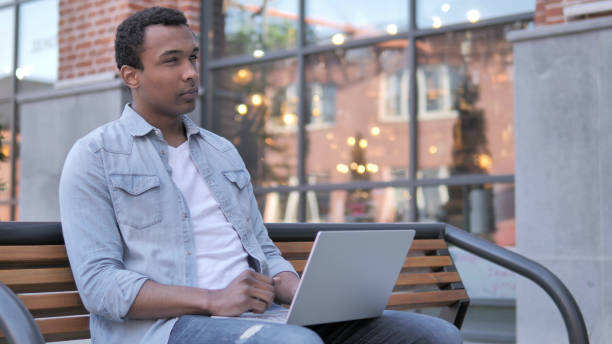 istock Pensive African Man working on Laptop, Sitting on Bench 1341882179