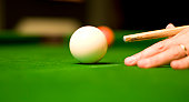 Pool player with cue poised to hit cue ball