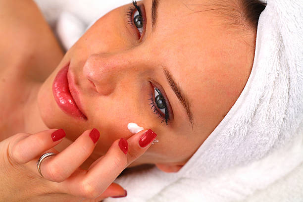 moisturizing mujer aplicar la crema en la cara - foto de stock