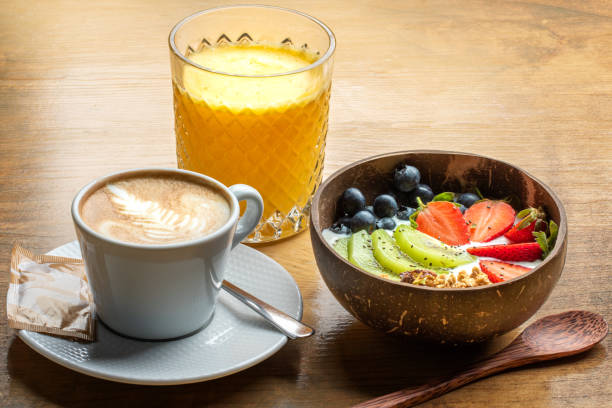 colazione appetitosa con ciotola di frutta fresca, succo d'arancia e caffè cremoso - currant food photography color image foto e immagini stock
