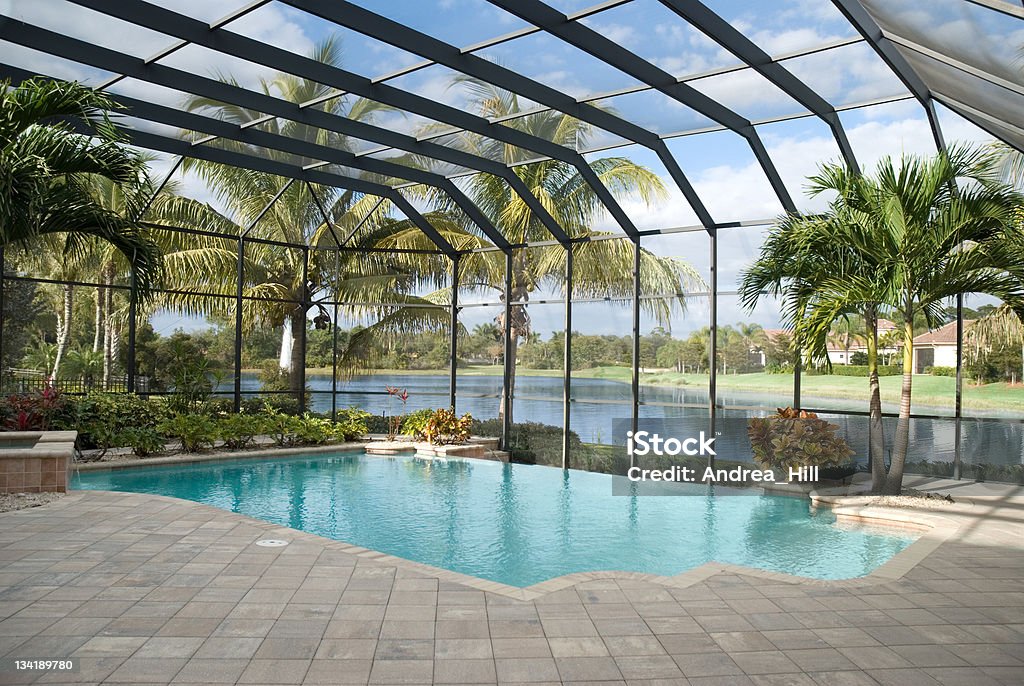 Backyard pool with window panel and ceiling next to lake A backyard pool located in a tropical setting covered by a screen lanai. Lake in behind. Florida - US State Stock Photo