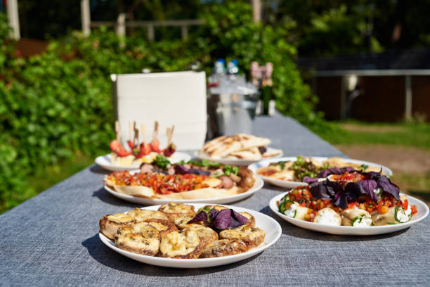 istock Plates with snacks on servered buffet table at wedding reception outdoors, copy space. Grilled mushrooms with cheese. Sandwiches, appetizer bruschetta, antipast, crostini, tapas 1341898181