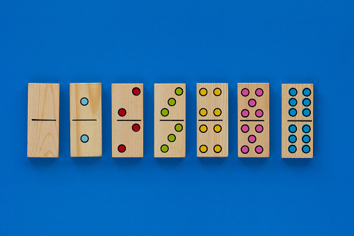 Top view of wooden six dominoes gaming pieces with double spots on it on blue background