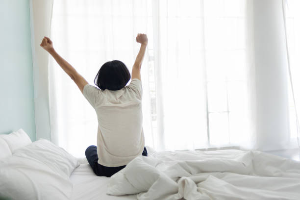 istock Asian man wake up and sitting stretching on bed 1341899792