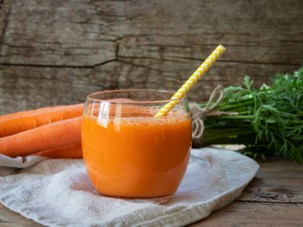 Fresh squeezed carrot juice in a glass on a wooden surface, rustic style  Healthy eating, detox, dieting and vegetarian concept. Fresh squeezed carrot juice in a glass on a wooden surface, rustic style  Healthy eating, detox, dieting and vegetarian concept. carrot juice stock pictures, royalty-free photos & images
