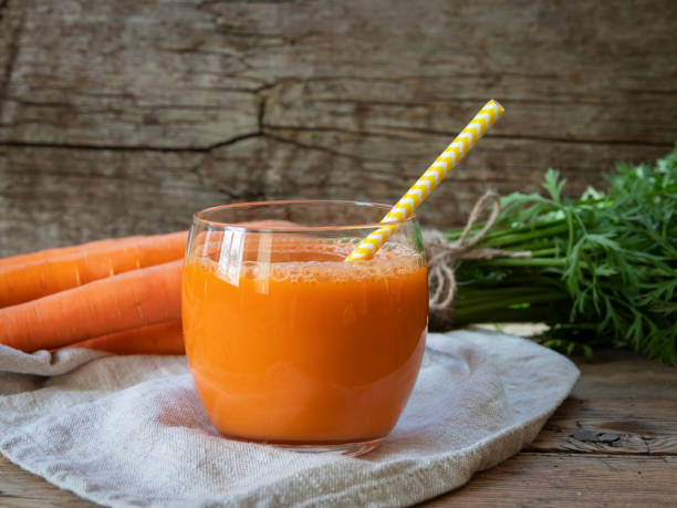 suco de cenoura espremido fresco em um copo em uma superfície de madeira, estilo rústico alimentação saudável, desintoxicação, dieta e conceito vegetariano. - carrot juice - fotografias e filmes do acervo